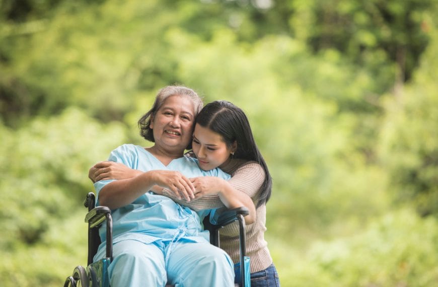 Woman in wheelchair with companion outdoors.