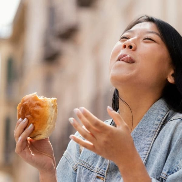 Woman enjoying a bite of a delicious pastry outdoors.
