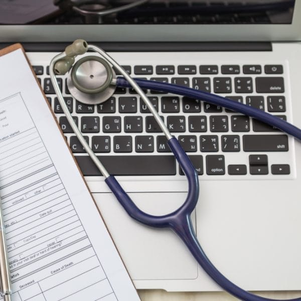 Medical history form with stethoscope on laptop.