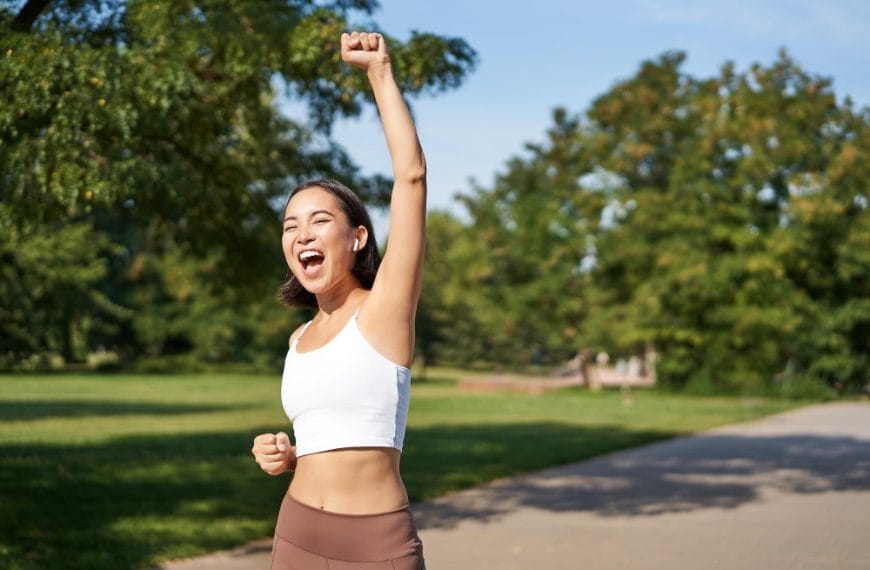 Woman celebrating success in park.