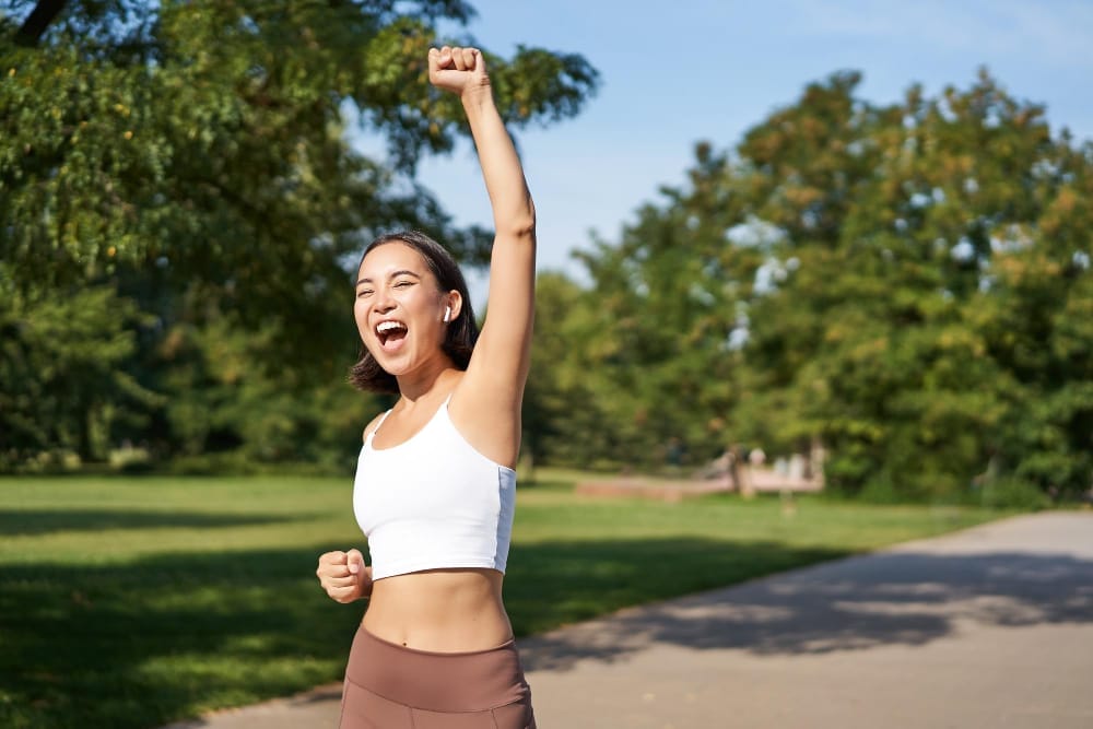 Woman celebrating success in park.